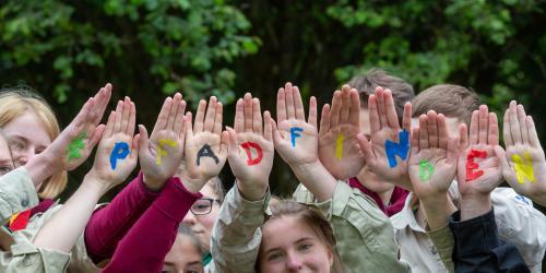 Kinder halten ihre Hände hoch, auf den Handflächen stehen Buchstaben, die "#Pfadfinden" bilden